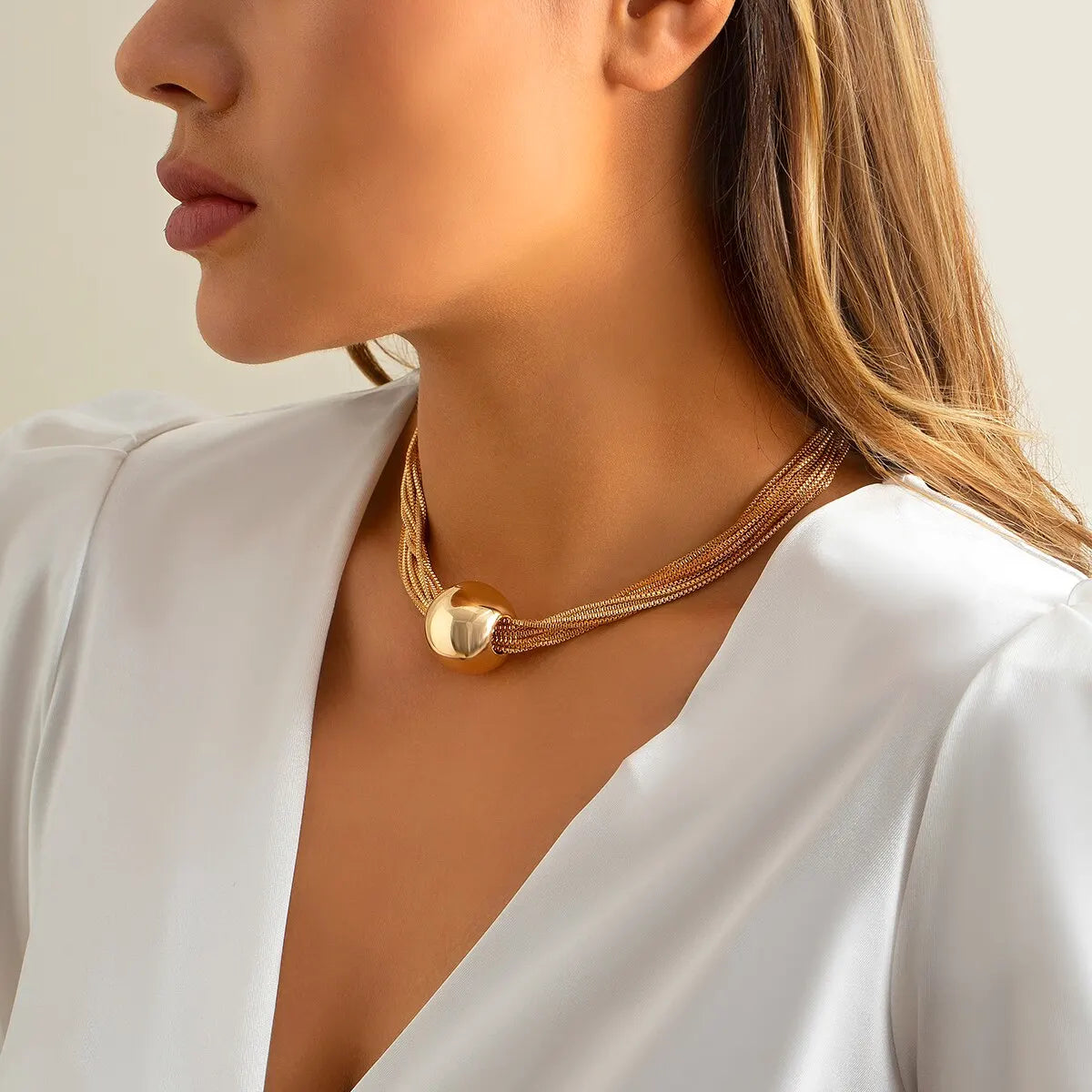 Model wearing exaggerated gold necklace