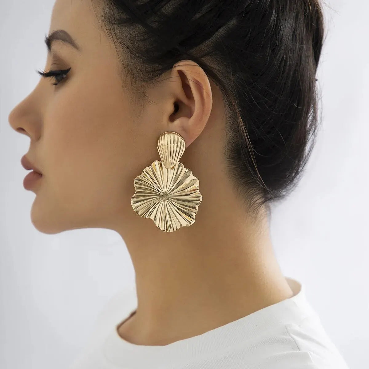 Model wearing large gold drop earrings